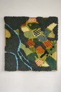 Handmade tufted wall hanging Meadow — abstract aerial landscape with winding river, green fields and orange accents in 100% New Zealand wool, 70x70cm in oak frame