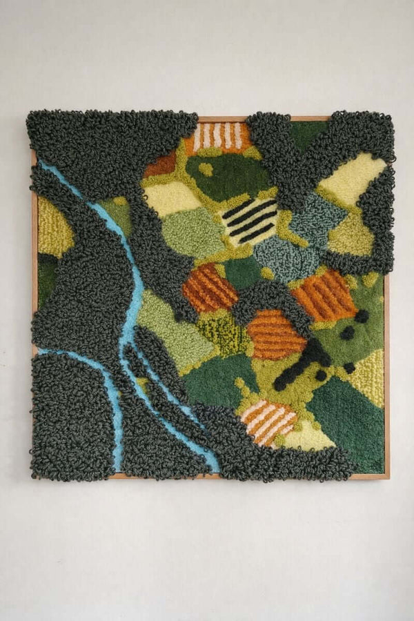 Handmade tufted wall hanging Meadow — abstract aerial landscape with winding river, green fields and orange accents in 100% New Zealand wool, 70x70cm in oak frame